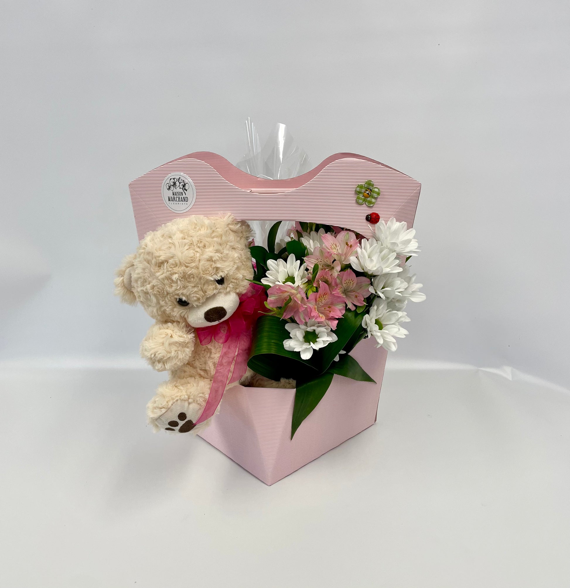 Belle boîte de fleurs colorées avec des alstroémères roses et des marguerites blanches, accompagnée d’une peluche beige et d’une boîte de 12 chocolats, présentée dans une boîte rose avec un ruban.